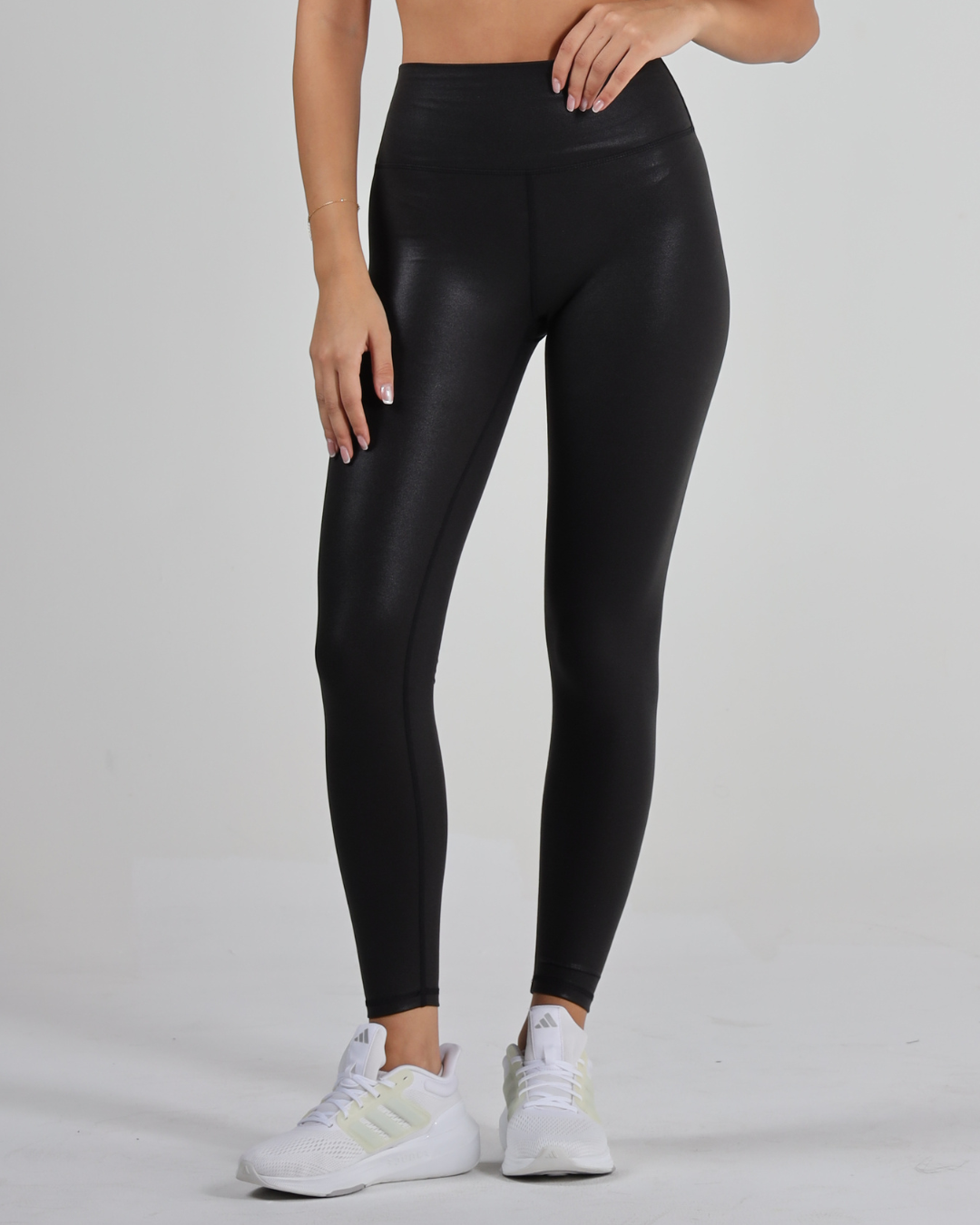 women wearing black leggings and white sneakers on a gray background