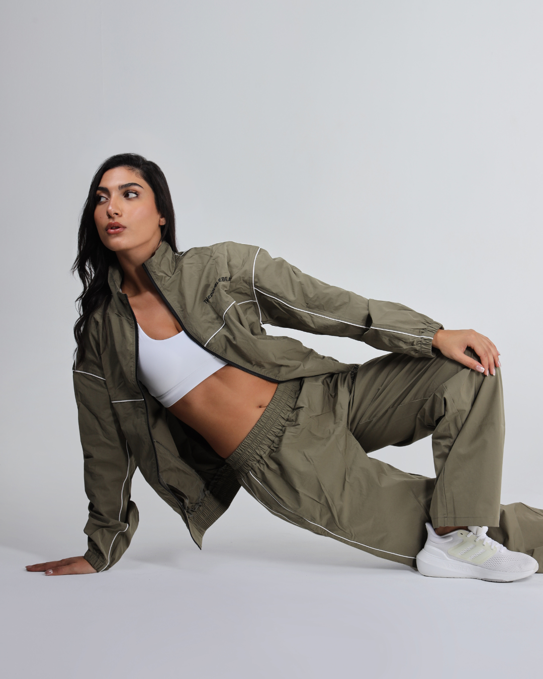 Woman wearing an olive green tracksuit on a white background