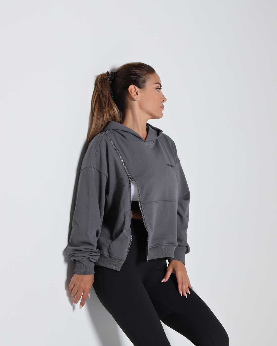 Woman wearing a gray hoodie and black pants on a white background