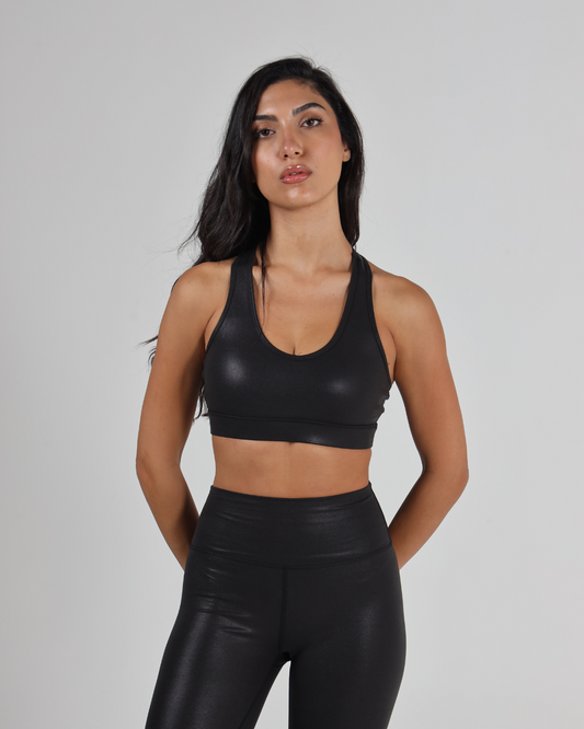 Woman wearing a black sports bra and leggings against a gray background