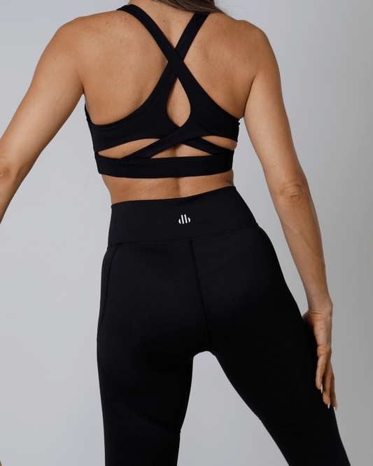 Women wearing a black sports bra and leggings with a gray background