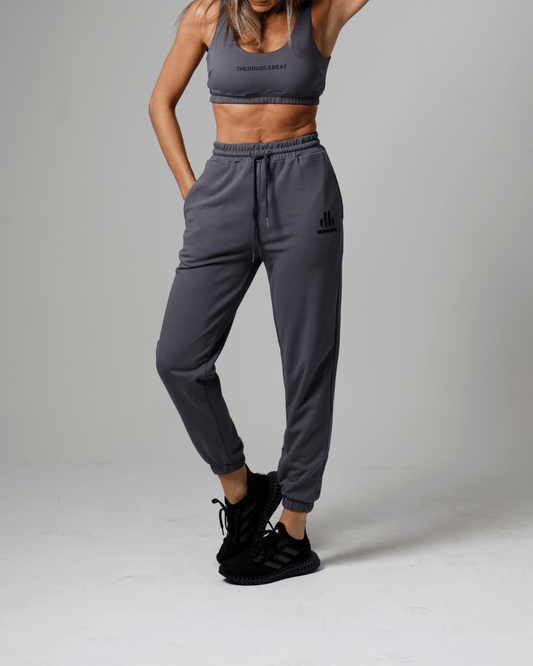 women wearing a gray athletic outfit with a logo on a plain background